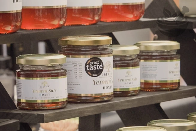row of prophetic blends yemeni sidr honey in glass jar at exhibition stall with logo