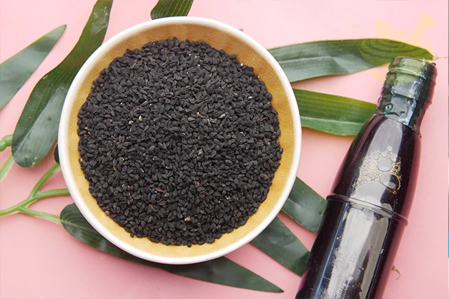 black cumin in container with oil in a jar on table.